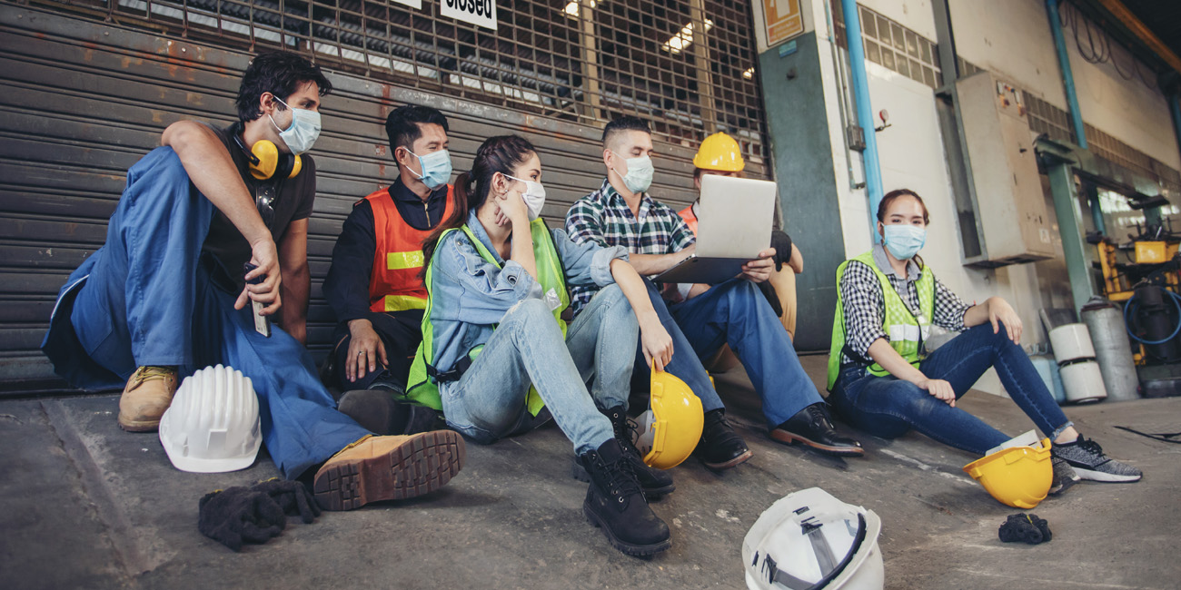 Group of diverse factory workers all wearing protective mask to protect against the spread of COVID-19.