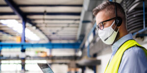 Technician wearing a protective mask working on his laptop